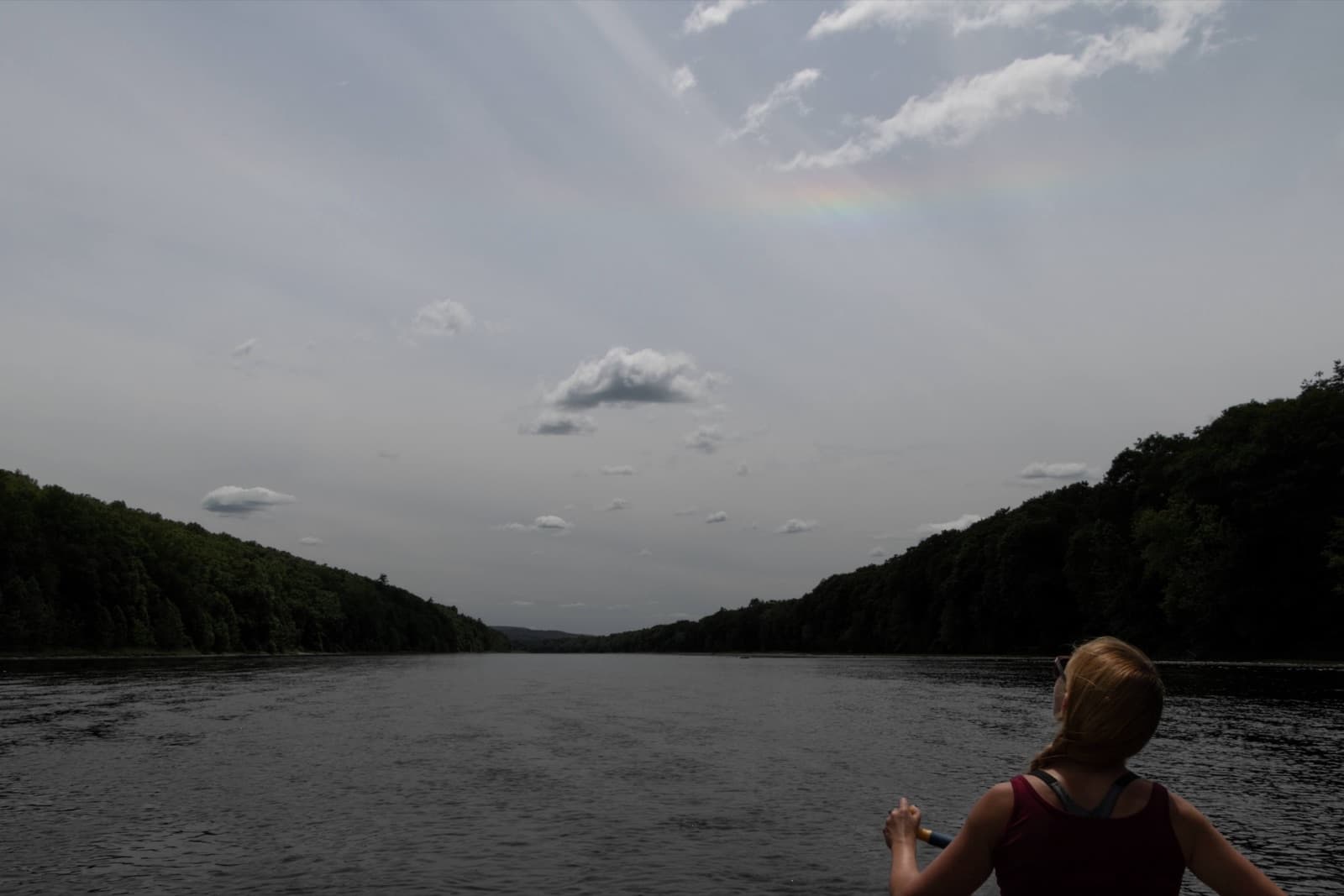 Paddler on the Delaware River with a rainbow visible over the water